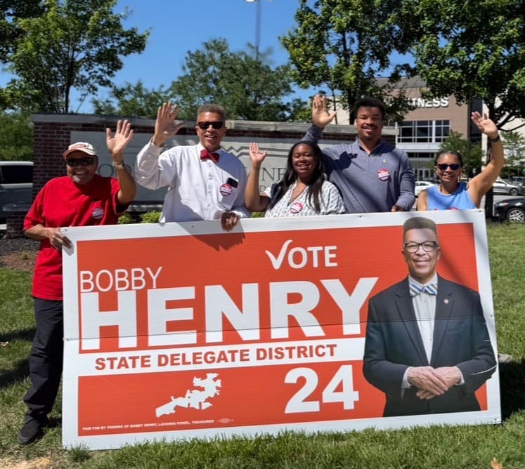Bobby Henry with campaign volunteers holding a Vote Bobby Henry yard sign